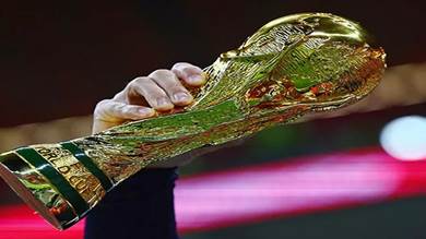 مشجّع يحمل نسخة من كأس العالم قبل المباراة بين فرنسا والمغرب في نصف النهائي 
